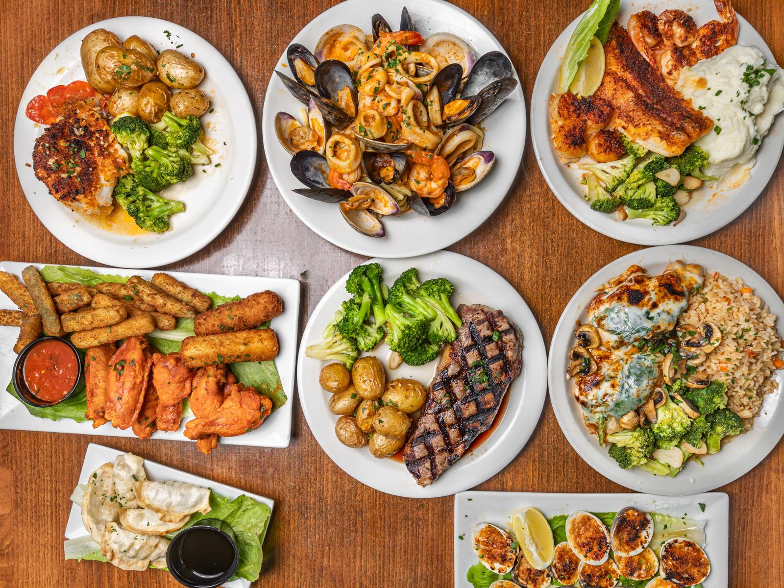 An overhead view of a table at Bayhouse covered in seafood, steak and appetiser plates